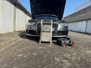 Audi RS grise capot ouvert pour décalaminage moteur avec appareil DUMAS DECALAMINAGE, valise à outils à côté.